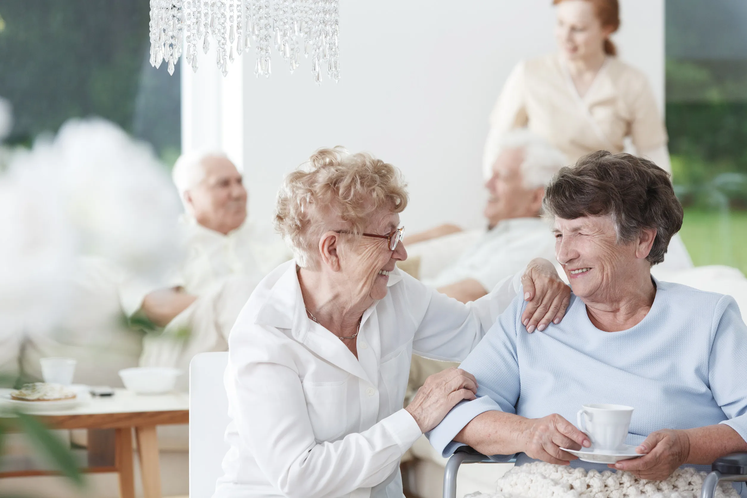 Two senior women friends talking and laughing over a cup of tea